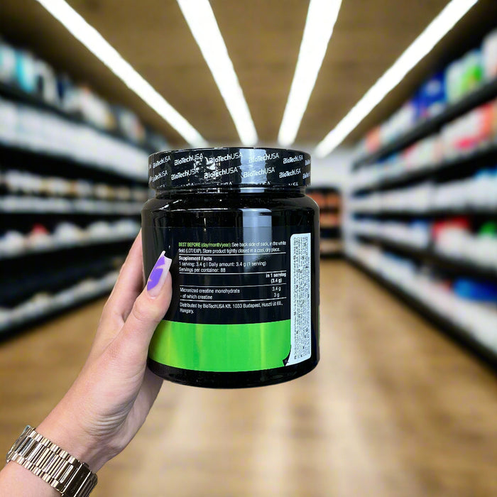 Close-up of (BioTechUSA 100% Creatine Monohydrate, Unflavoured 300g) held up inside My Supplement Shop, clearly showing Nutritional Values on the packaging in a Sports Nutrition setting.