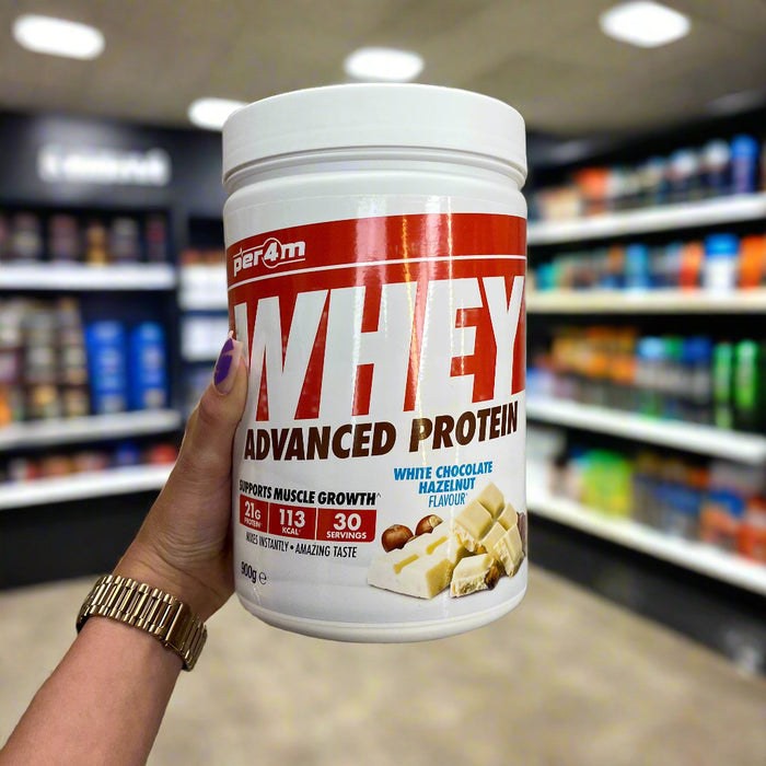 Close-up of (PER4M Whey Protein Powder 900g) held up inside My Supplement Shop, clearly showing the front label in a Sports Nutrition setting.